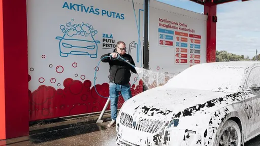 Мужчина моет автомобиль пеной на самообслуживаемой автомойке PUTO.