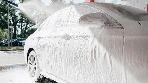 Car at the PUTO car wash, covered in foam and being washed with a high-pressure water spray.
