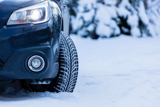 Front wheel of a car with a winter tyre on a snowy road in winter conditions