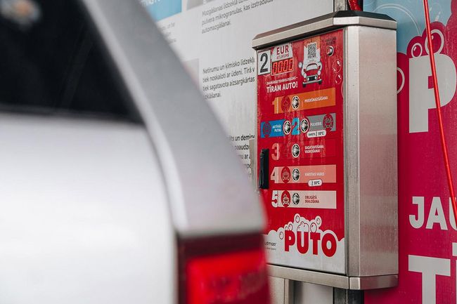 Auto tiek mazgāts ar putām PUTO pašapkalpošanās automazgātavā, uzsverot mazgāšanas priekšrocības.