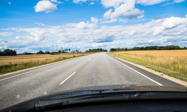 Skats caur tīru auto vējstiklu uz ceļu garā vasaras braucienā