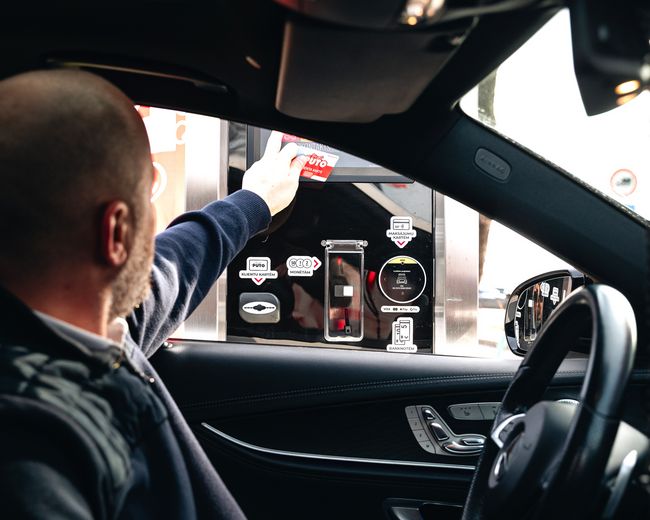 Autovadītājs pie maksājuma termināļa automazgātavā.