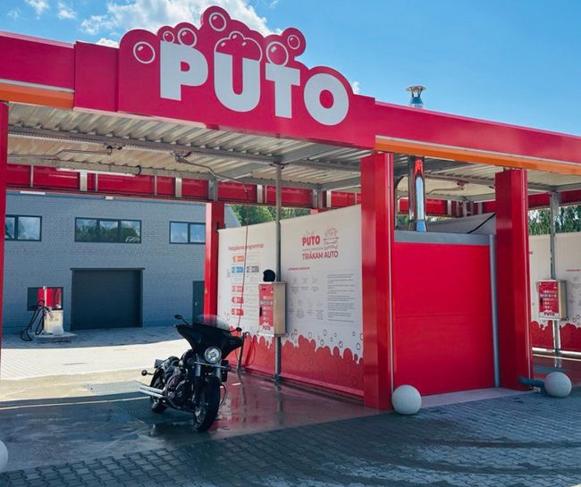 PUTO car wash in Rūjiena with a motorcycle in the bay, featuring red and white decor.