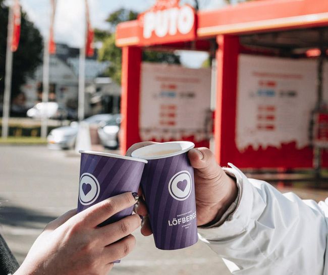 Two people holding LOFBERGS coffee cups at PUTO car wash.
