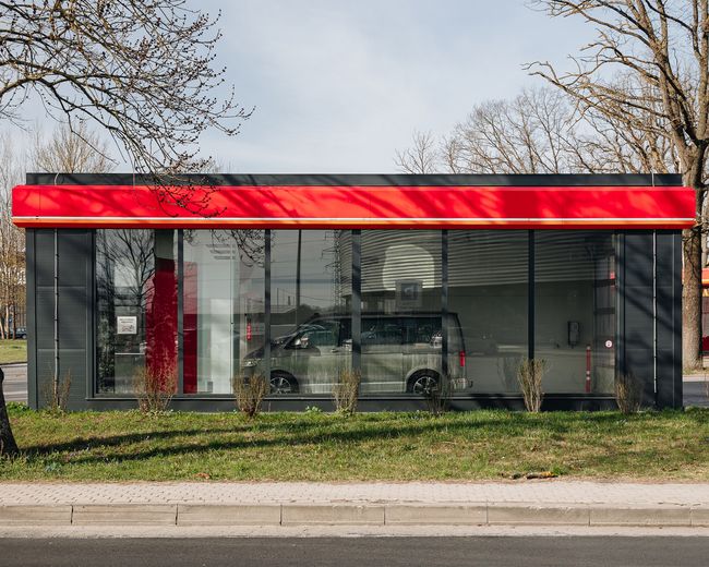 Automašīnu mazgātava ar stikla sienām un sarkanu jumtu.