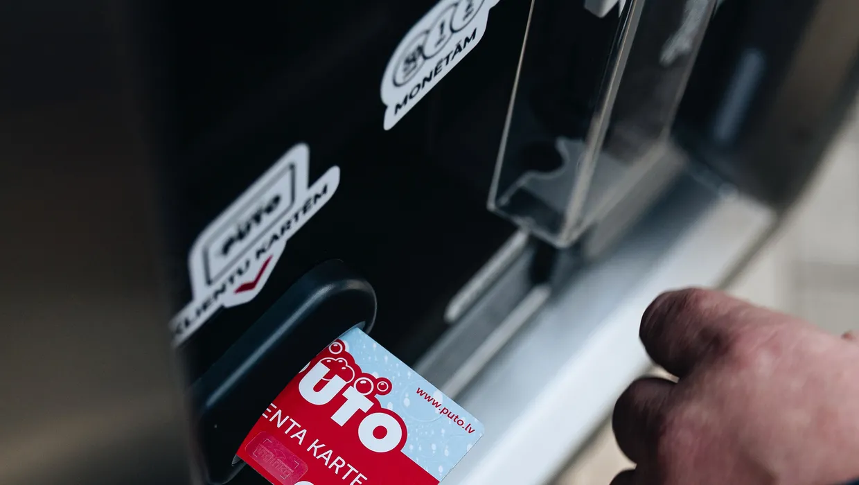 Kartes ievietošana automātiskajā maksājumu terminālī pie automazgātavas.