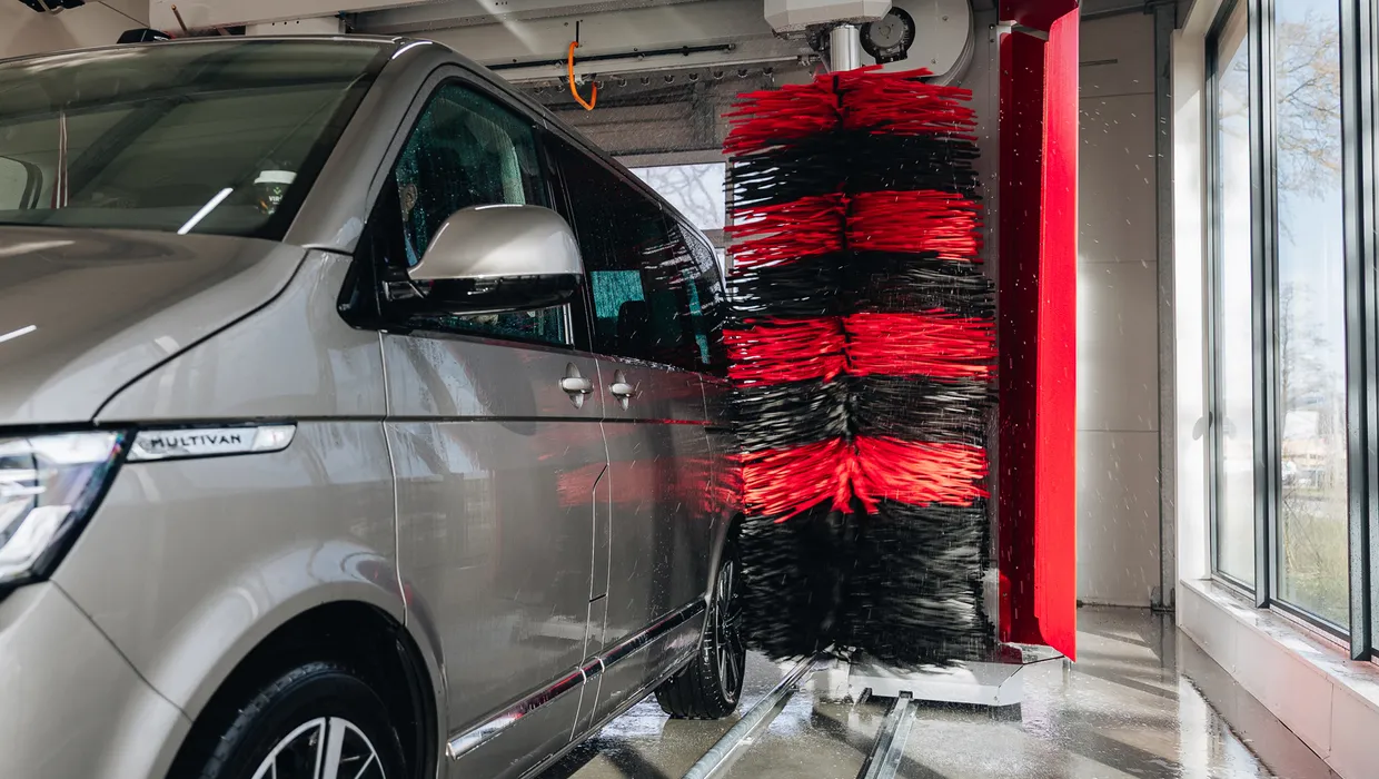 Sudrabots buss automazgātuvē ar sarkanām un melnām birstēm.