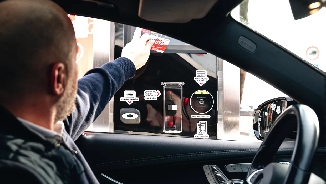 Autovadītājs pie maksājuma termināļa automazgātavā.