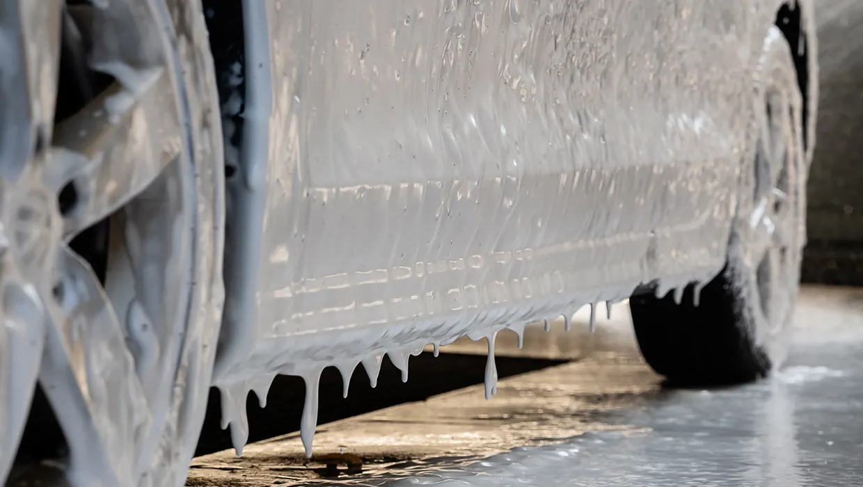 Aktīvās putas (active foam) noplūst no automašīnas sāna un riteņa, mīkstinot ieēdušos netīrumus un ceļa sāli