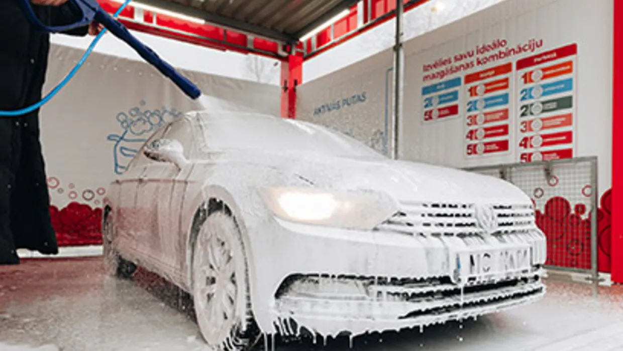 Automazgātavā ar putu pistoli tiek pārklāta automašīna ar putām